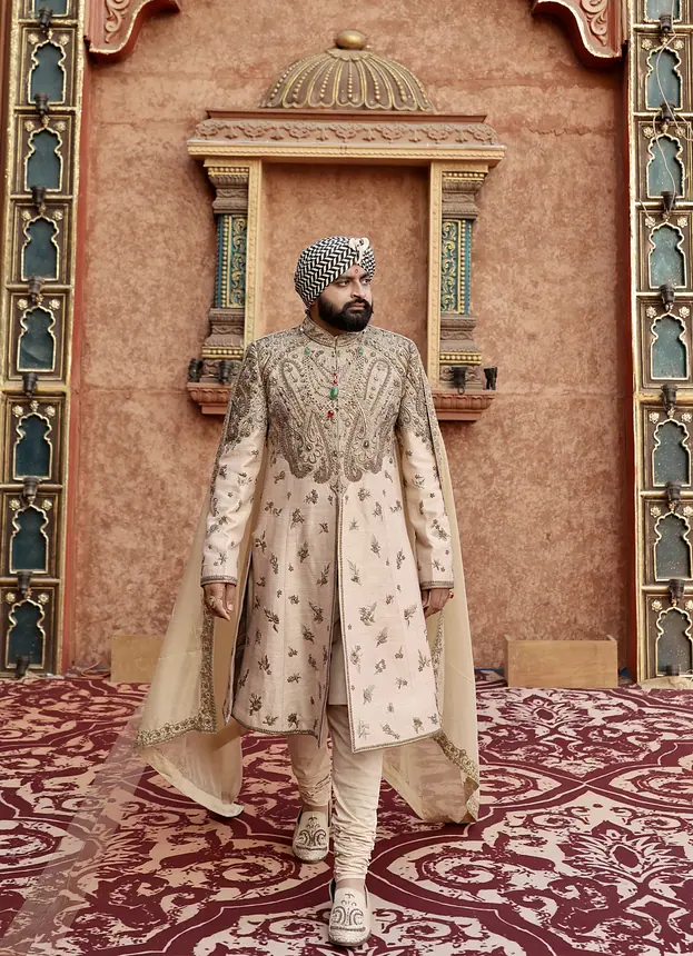 Groom in embroidered sherwani at a palace doorway