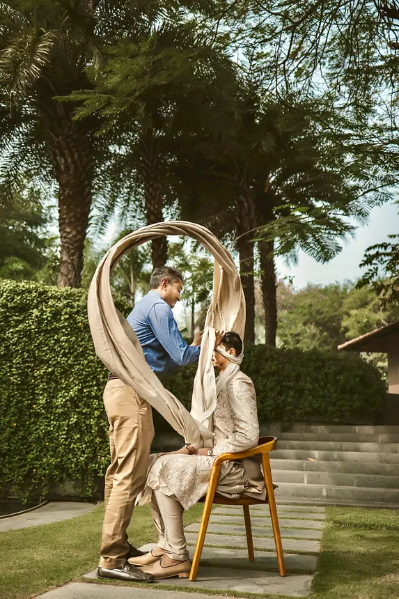 Kishore draping a flowing shawl on the groom outdoors