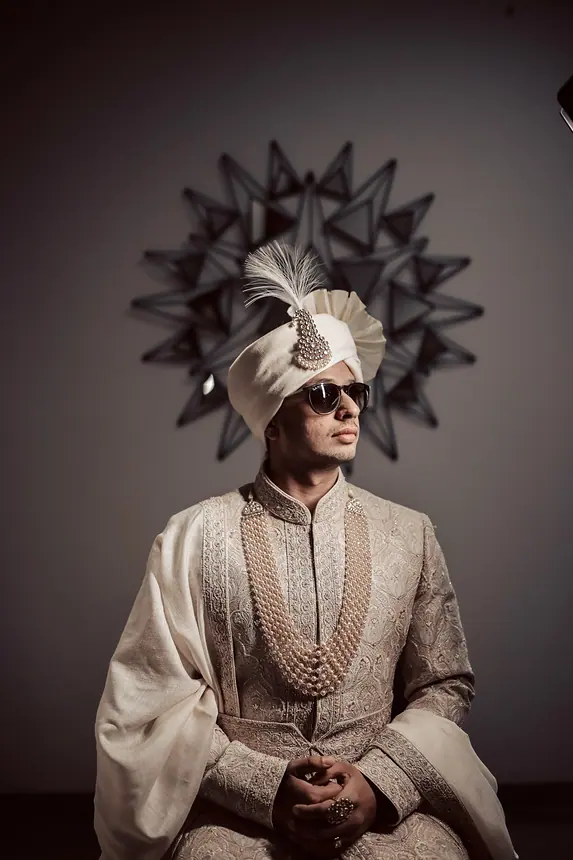 Groom in ivory safa with feather kalgi and sunglasses, dramatic portrait