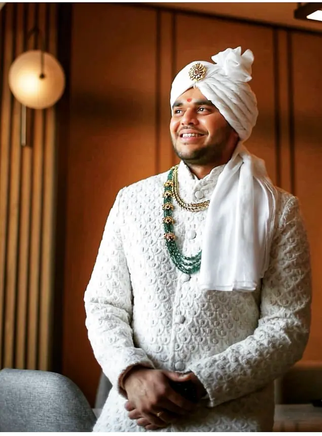 Smiling groom in white safa and chikankari sherwani