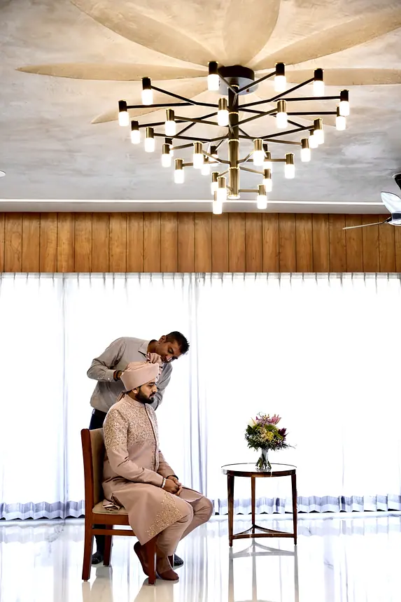 Kishore tying the groom's safa under a chandelier